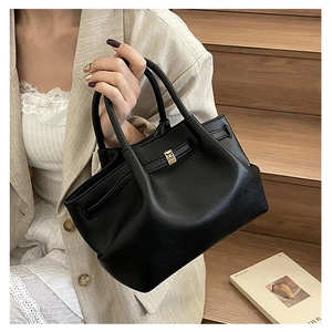 Chic black litchi grain leather wing tote with golden buckle detail on model