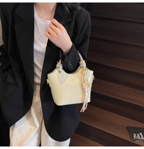 Detailed macro view of the cream-white bucket bag with cute cartoon embossed leather patterns