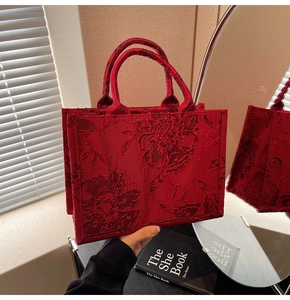 Close-up of red wedding handbag with elegant floral relief embroidery and dual handles
