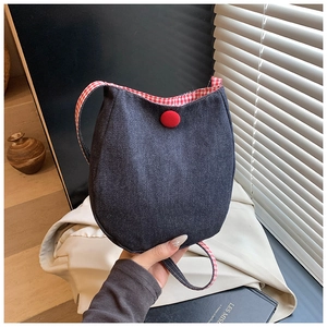 Close-up of blue denim crossbody bag with red and white checkered lining and red button detail