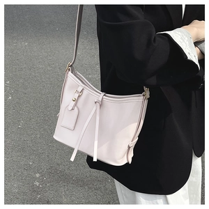 Détail du sac seau minimaliste en cuir ciré crème avec garniture dorée sur l'épaule