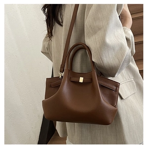 Detail of premium brown pleated bucket bag with lychee texture and gold metal clasp