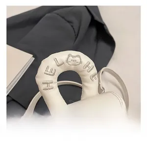 Detail view of white mini leather bag featuring embroidered handle and silver metal clasp
