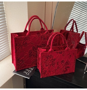 Detailed macro view of high-quality red floral jacquard fabric on a luxury tote bag set