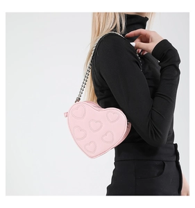 Macro shot of pink heart-shaped bag with embossed textures and silver chain strap