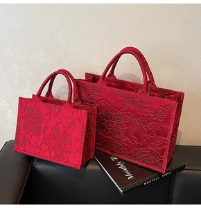 Detailed view of red bridal tote bags with embossed floral lace texture and sturdy handles