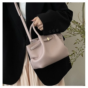 Detail of dusty pink lychee grain leather bucket bag with gold buckle on model