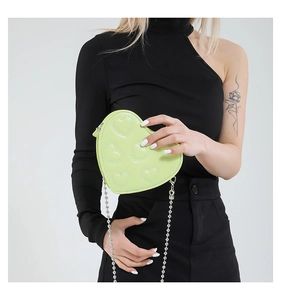 Quilted heart-shaped crossbody bag in lime green with silver bead chain worn by model
