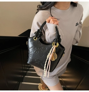 Close-up of black embossed bucket bag with leather texture and tennis racket charm