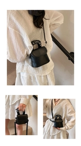 Detail of black mini crossbody bag featuring white lettered handle and cat logo