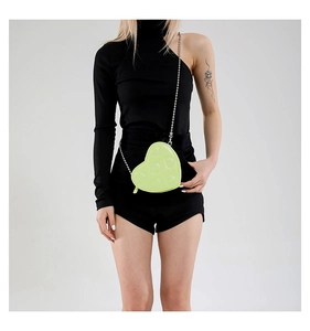 Detail of neon green heart-shaped crossbody bag with quilted pattern and silver chain strap