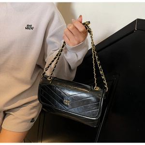 Close-up of black oil wax leather mini bag with gold chain strap and V-quilted texture