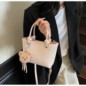 Detail of pink woven bucket bag with cute bear charm and adjustable shoulder strap