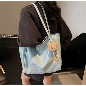 Close-up of light blue oil wax leather tote bag with vintage plush bear pendant detail