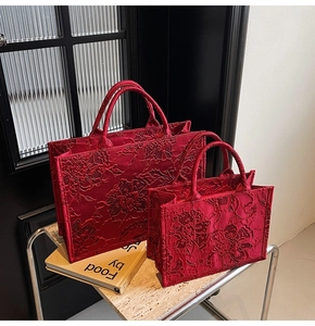 Detailed macro view of 3D floral lace embroidery on red bridal tote bags in two sizes