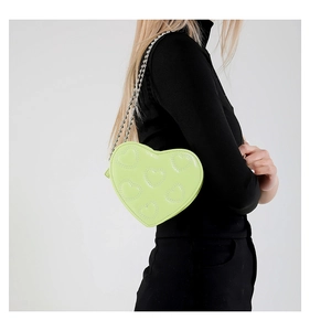 Detail view of heart shaped crossbody bag with quilted embroidery and silver bead chain