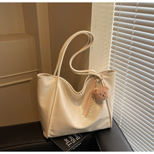 Macro view of cream white tote bag texture with cute teddy bear charm and silk ribbon
