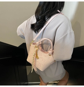 Detail view of pink bucket bag with embossed cartoon animals and elegant silk scarf charm
