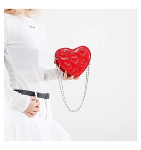 Detail of red heart-shaped patent leather bag with embossed hearts and silver bead chain