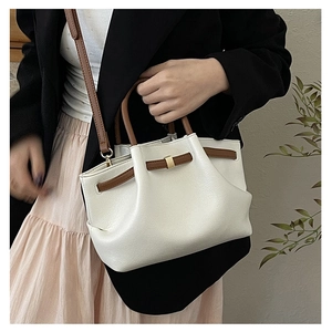 Detailed close-up of cream pleated bucket bag with brown leather handles and gold buckle