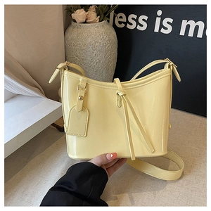 Détail de la boucle dorée et du cuir huilé lisse sur un sac seau de couleur crème