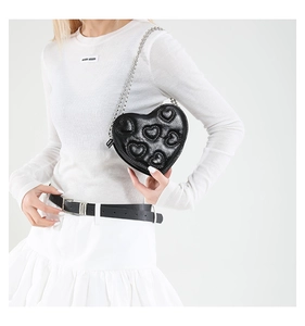 Detail view of heart-shaped crossbody bag with embossed patterns and silver chain strap