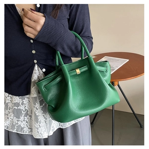 Close-up of bright green leather bucket bag with pebble texture and gold square buckle