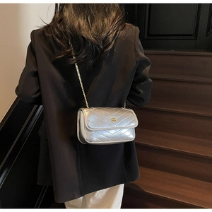 Silver quilted chain bag shown from back view on a model wearing a black blazer