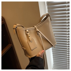 Détail d'un sac seau beige avec quincaillerie polie et coutures raffinées