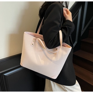 Close-up of pink tote bag with woven leather texture and elegant gold hardware detail