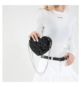 Detail of black heart-shaped handbag featuring embossed heart pattern and silver chain