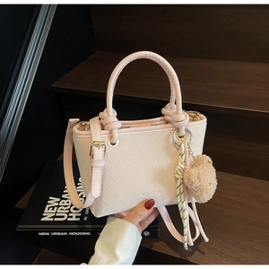 Detail of light pink bucket bag with embossed texture and cute plush bear accessory