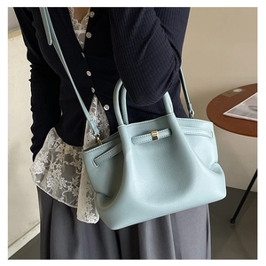 Close-up of light blue pebble leather tote bag with stylish metal buckle and side wings