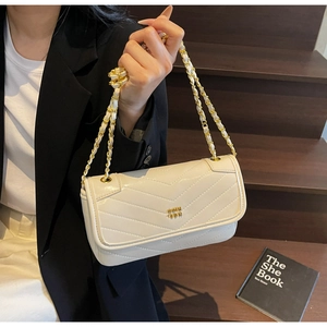 Detail of white leather crossbody bag with gold chain strap and V-quilt pattern stitching