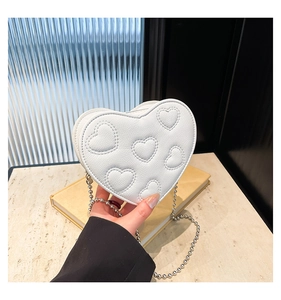Detail shot of heart-shaped white crossbody bag with silver bead chain and embroidery