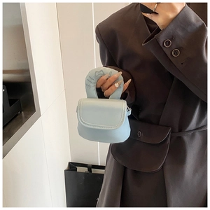 Close-up of light blue mini bag featuring an embossed cat logo on a thick round handle