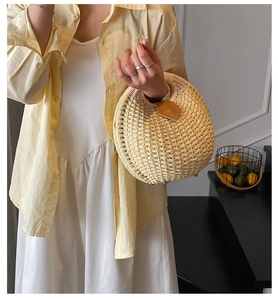 Detail of a handmade round straw handbag with leather trim and lemon decor context