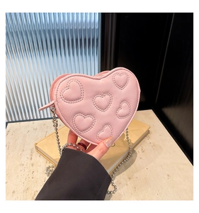 Close-up of pink heart-shaped crossbody bag with quilted embroidery and silver chain