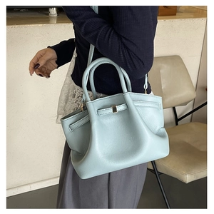 Detail of light blue bucket bag showing soft lychee texture and metallic fastener