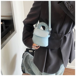 Detail of light blue mini crossbody bag with cat pattern embossing and silver hardware