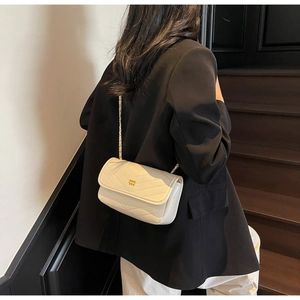 Detailed view of white chevron quilted leather crossbody bag with gold chain strap