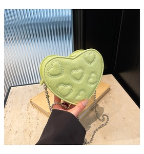 Detail of light green heart-shaped crossbody bag with quilted texture and silver bead chain