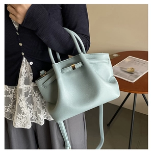 Detail of mint green lychee grain leather handbag with gold hardware and slim handles