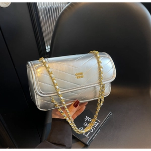 Close-up of silver quilted leather handbag with gold chain strap and metal logo