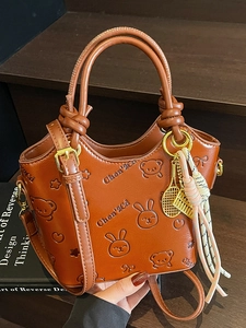 Brown embossed bucket bag with cartoon bear pattern and decorative charms for women