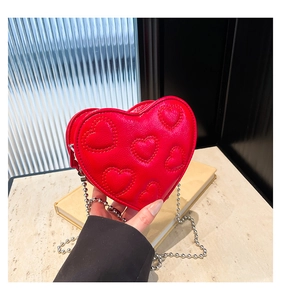 Detailed view of red heart-shaped leather crossbody bag with chic silver bead chain strap