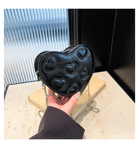 Detail of black heart-shaped handbag with embossed patterns and silver ball chain strap