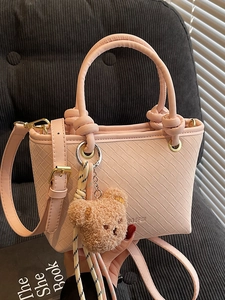 Chic pink textured bucket bag with teddy bear charm and elegant gold hardware details