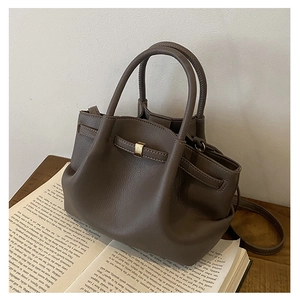 Detailed view of dark brown lychee pattern leather bucket bag on an open book