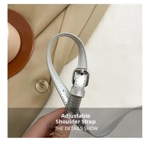 Détail d'une bandoulière argentée réglable avec boucle en métal et fini brillant